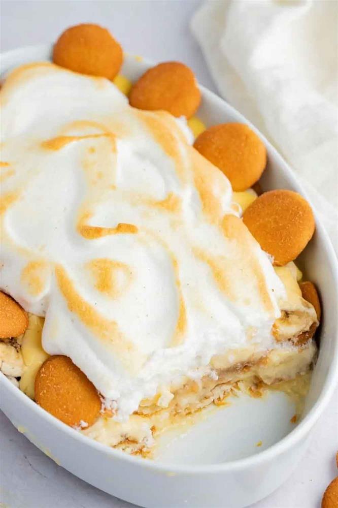 A bowl of banana pudding and biscuits with a layer of golden meringue