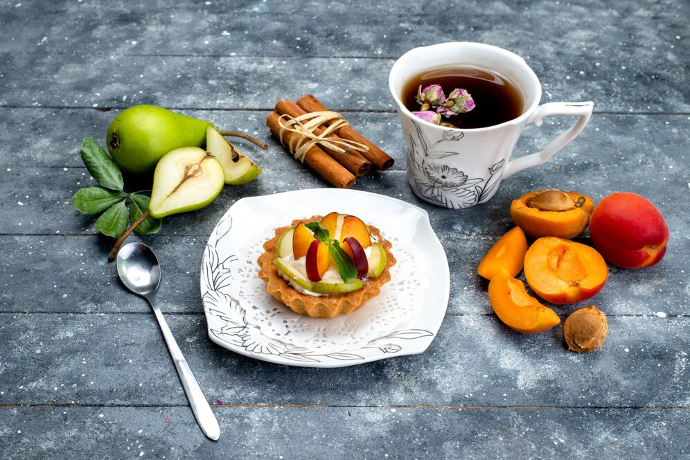 delicious-cake-with-cream-sliced-fruits-inside-plate-with-tea-grey